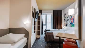 Ein Hotelzimmer mit Bett, Schreibtisch, Stuhl, Sofa und Fernseher.