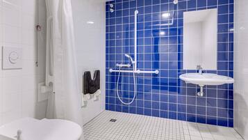 A modern bathroom with a white toilet, a shower with a handheld showerhead, and a sink with a mirror.