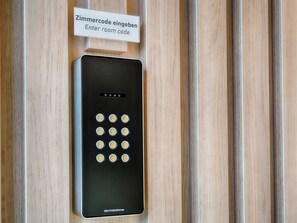 A black room entry keypad with a sign above it that reads "Zimmercode eingeben Enter room code". - B&B Hotel Bremen-Überseestadt (Bremen)