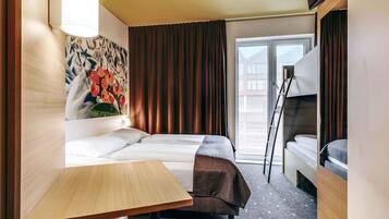 A hotel room with a bed, a desk, a chair, a painting, and a view of the outside.