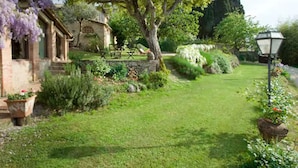 A garden with a stone building, a large tree, and a lamp post. - Cottage la Vita Siena for 6 with private pool in a peaceful area in Siena city (siena)