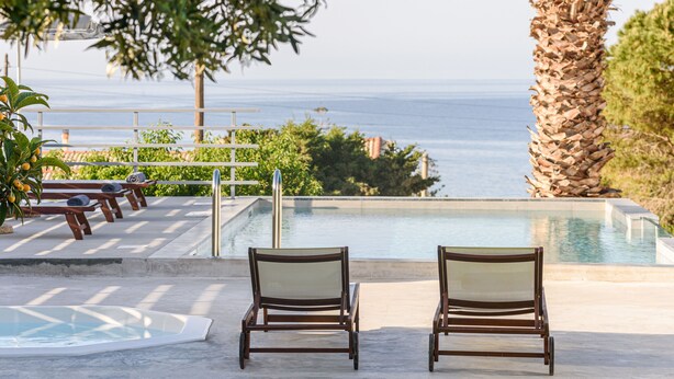 Un espace aménagé au bord de la piscine, avec des chaises longues, un jacuzzi et une vue sur l’océan.