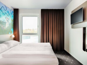 A hotel room with a bed, a window with curtains, a wall-mounted TV, and a painting on the wall. - B&B Hotel Ravensburg (Ravensburg)