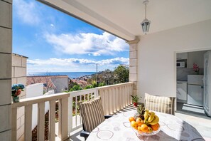 Un balcone con tavolo apparecchiato per la colazione, vista sul mare e angolo cottura.