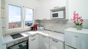 Una cocina moderna con armarios blancos, un microondas integrado, una cafetera y un lavabo.