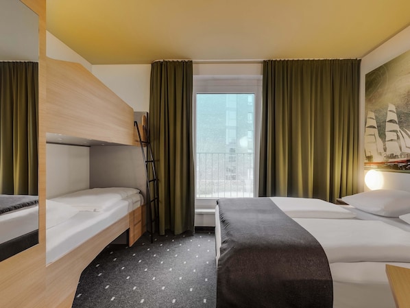 Habitación de hotel con dos camas, una ventana con cortinas, un cuadro de un barco y vistas a la ciudad.
