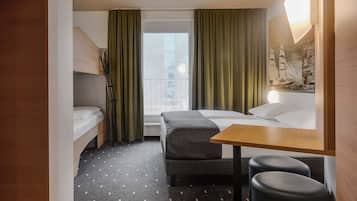 Habitación de hotel con cama, escritorio, silla, sofá, ventana con cortinas y vista a la ciudad.