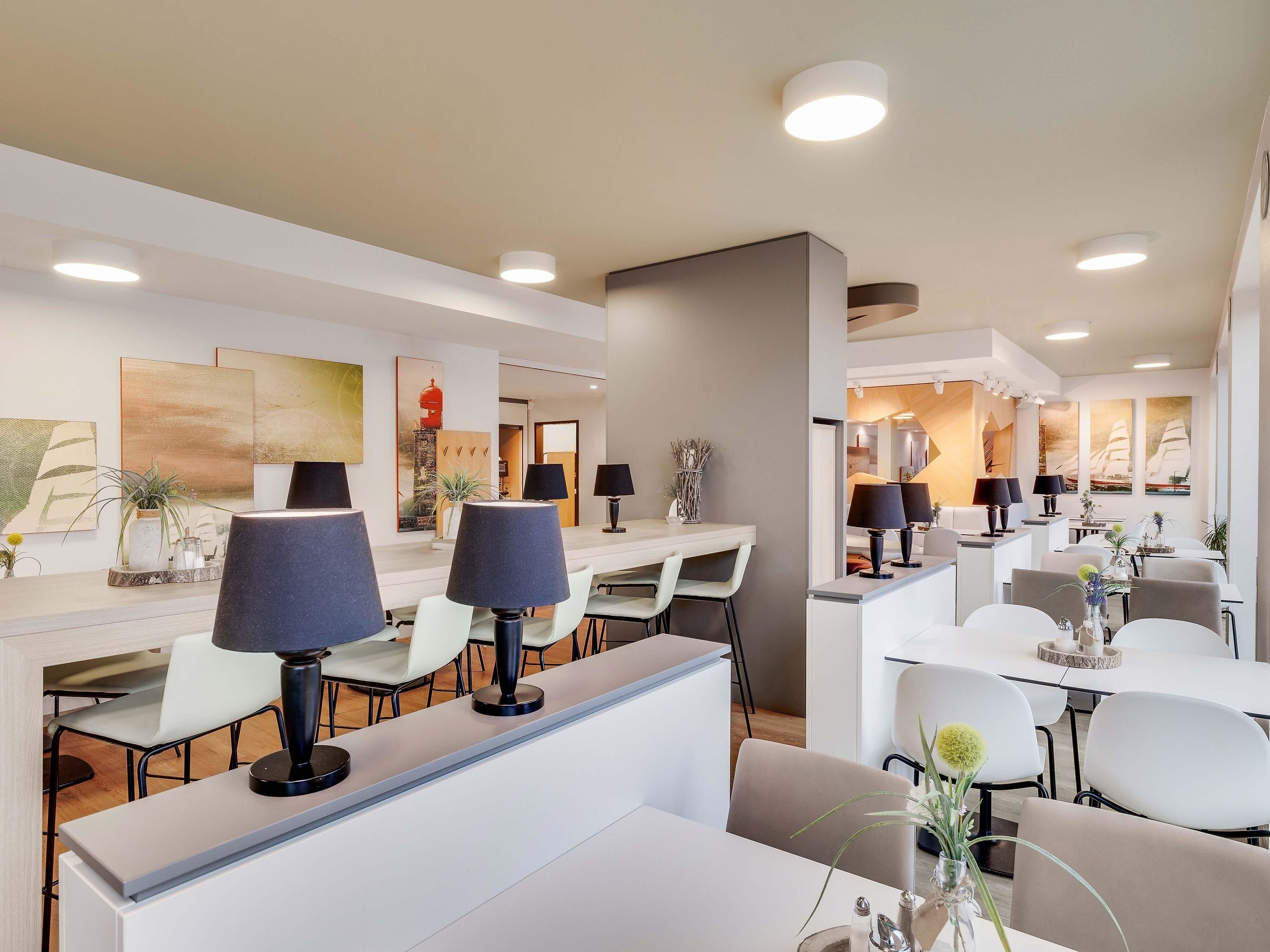 A modern hotel lobby with a reception desk, seating area, and artwork on the walls.