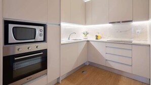 A modern kitchen with a built-in microwave, oven, and sink. - Colorful Bright Flat w/ Balcony by HostWise (Porto)