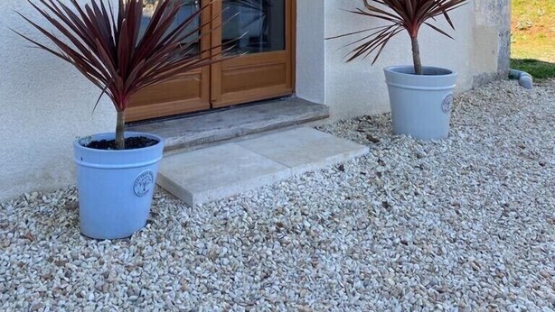 A building with a wooden pergola, a glass door, and two potted plants. - Peaceful Countryside Gite with private pool near Aubeterre (Laprade)