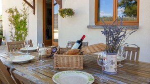 A wooden table set with plates, glasses, a bottle of wine, a basket of bread, and a vase with lavender. - Peaceful Countryside Gite with private pool near Aubeterre (Laprade)