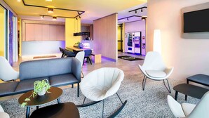A modern hotel lobby with seating areas, a reception desk, and a vending machine. - B&B Hotel Rust-Ettenheim (Mahlberg)