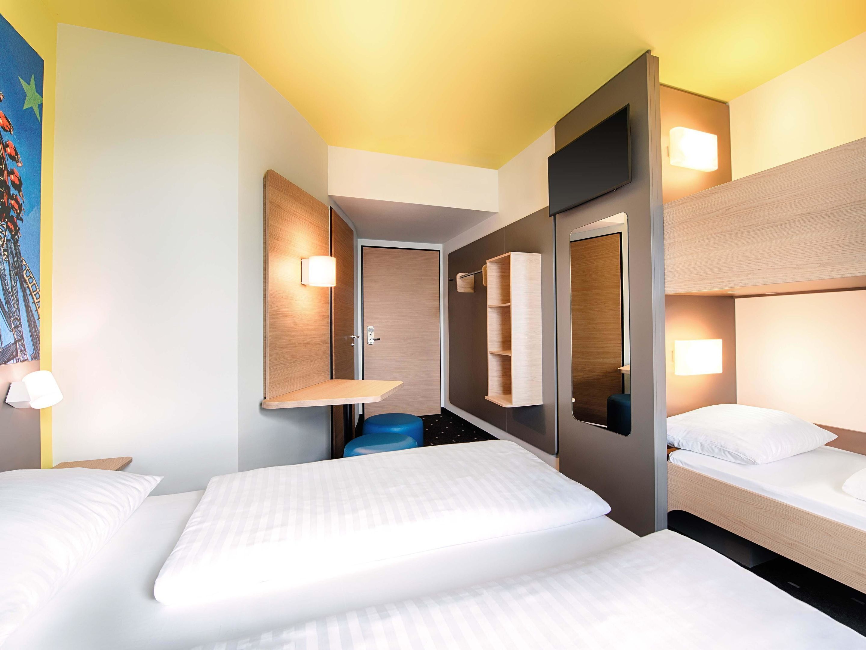 Una habitación de hotel con dos camas, una zona de estar pequeña y un espejo grande.