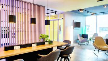 Un área de recepción moderna con un panel de listones de madera, un mostrador de recepción y varias zonas de estar con sillas.