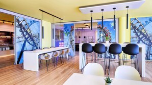 A modern dining area with a long white table, black chairs, and a central plant. - B&B Hotel Rust-Ettenheim (Mahlberg)
