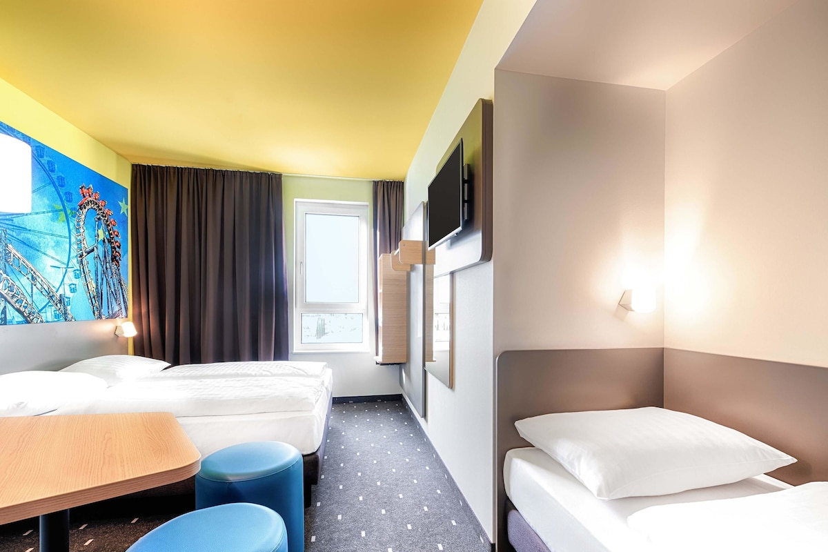 Ein Hotelzimmer mit zwei Betten, einem Schreibtisch und einem Sessel.