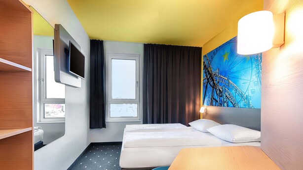 A hotel room with a bed, a desk, a TV, and a window. - B&B Hotel Rust-Ettenheim (Mahlberg)