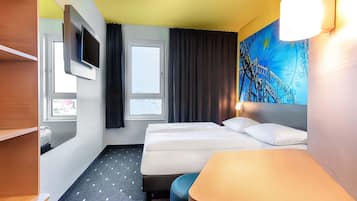 Una habitación de hotel con cama, escritorio, televisión y ventana.