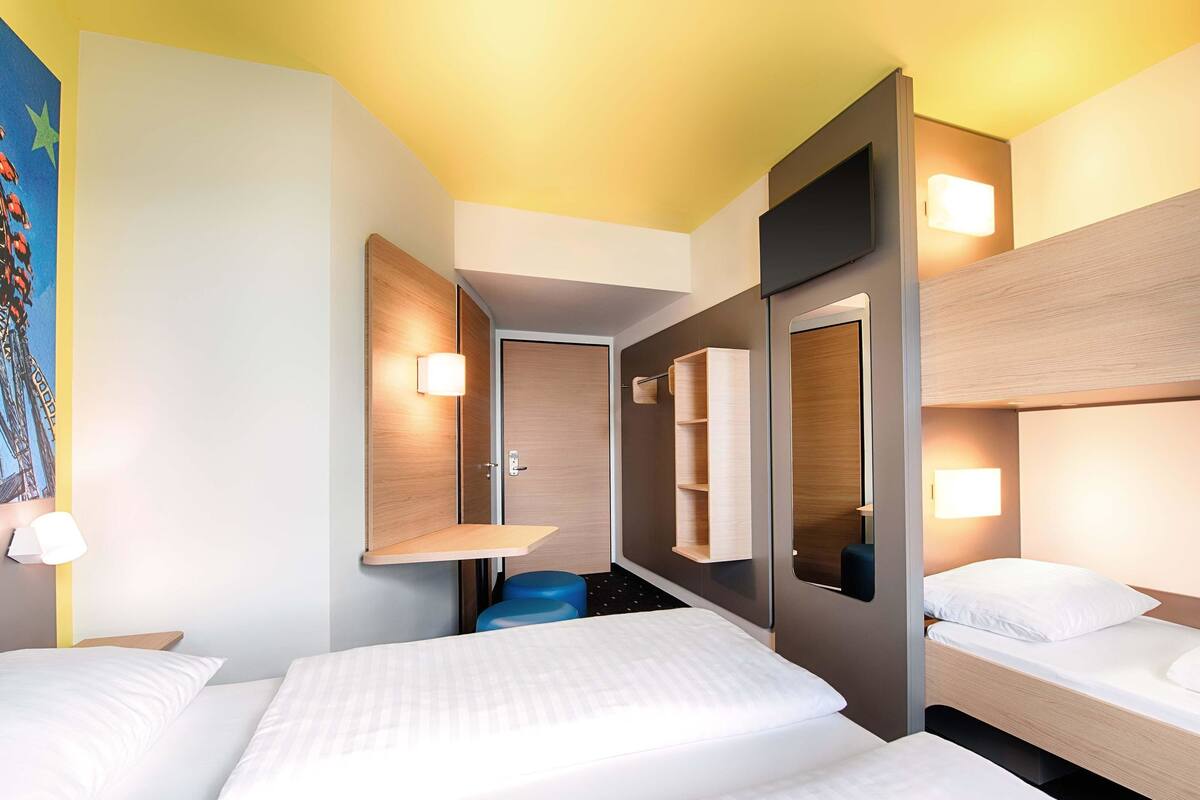 A hotel room with two beds, a small seating area, and a large mirror.