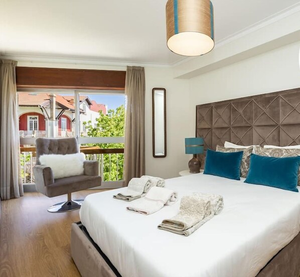 A hotel room with a large bed, two bedside lamps, a chair, and a view of the outside.
