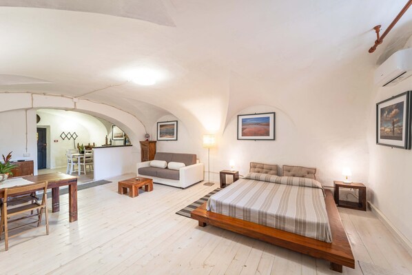 Un dormitorio amplio con una cama grande, una zona de comedor y una cocina al fondo.