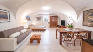 A spacious living area with a sofa, coffee table, dining table, and chairs. - Loft Apartment ‘Casa Gilbert 101’ close to Beach with Wi-Fi (alghero)
