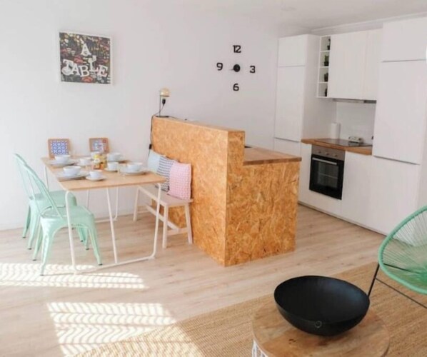Una cocina moderna con armarios blancos, una isla de madera y un comedor con mesa y sillas.