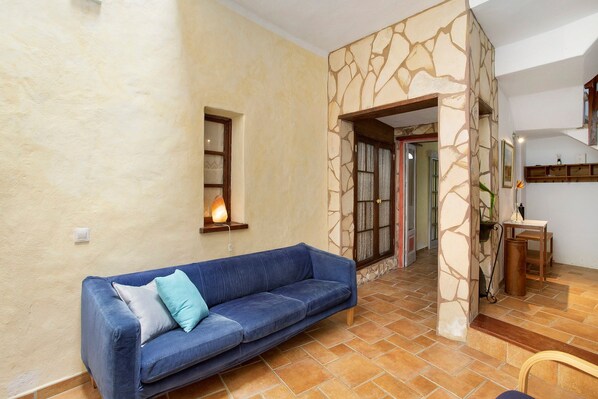 A living room with a blue sofa, a stone wall, and a tiled floor.