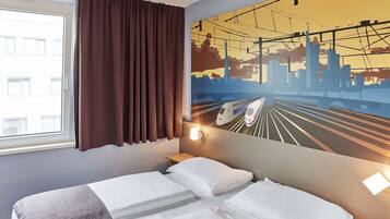 Een hotelkamer met een bed, een raam met gordijnen, een wandtelefoon en een stadsgezicht muurschildering.