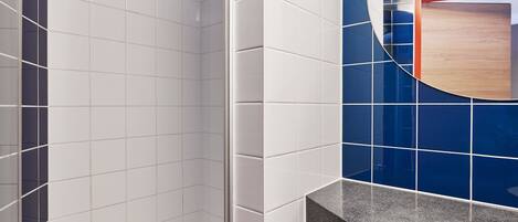 Un baño con azulejos blancos y azules, encimera de granito y un armario de medicinas de madera.
