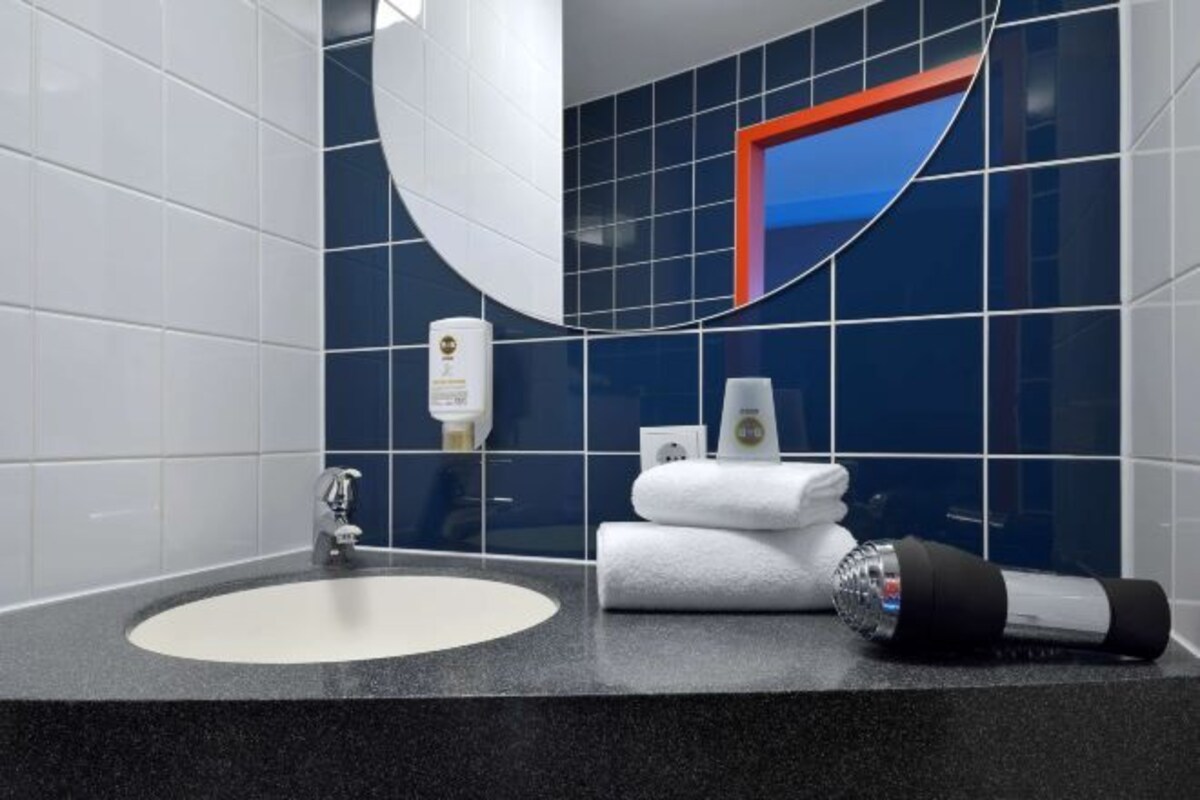 A bathroom with a sink, mirror, and toiletries.