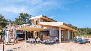 A villa with a covered patio, outdoor seating, and a view of the surrounding landscape. - Beautiful Holiday Home “Son Llodra” with Mountain View, Pool, Terrace & WiFi (Son Macia)