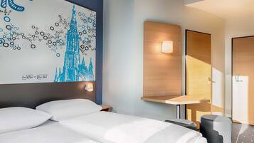 Ein Hotelzimmer mit Bett, Nachttisch, Wandlampe und einem großen abstrakten Gemälde.