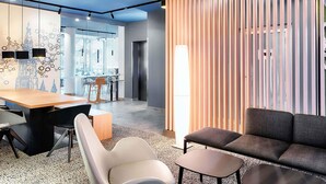 A modern office space with a meeting table, chairs, a sofa, and a tall floor lamp. - B&B Hotel Ulm (Ulm)