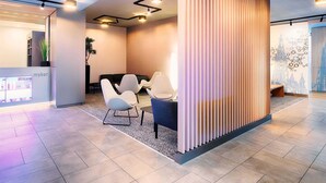 A modern reception area with a seating area, a plant, and a wall with a decorative pattern. - B&B Hotel Ulm (Ulm)