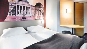 Ein Hotelzimmer mit einem Bett, einem Schreibtisch und einer Wandlampe.