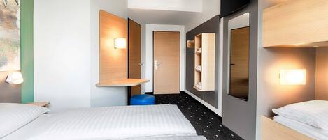 A hotel room with two beds, a wooden bench, a wall-mounted shelf, and a small trash bin.