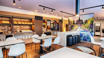 A modern cafe with a breakfast bar, seating area, and a mural.