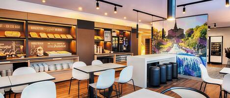 A modern cafe with a breakfast bar, seating area, and a mural.
