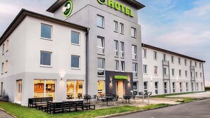A modern hotel building with a prominent 'B&B HOTELS' sign, a reception area, and outdoor seating. - B&B Hotel Kassel-Süd (Lohfelden)