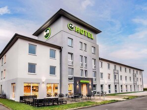 A modern hotel building with a prominent 'B&B HOTELS' sign, a reception area, and outdoor seating. - B&B Hotel Kassel-Süd (Lohfelden)