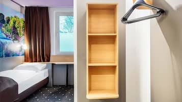 Habitación de hotel con cama, una estantería de madera en la pared y una ventana con cortinas.