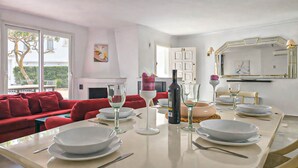 Un coin repas avec une table dressée pour quatre personnes, un canapé rouge et une cheminée en arrière-plan.