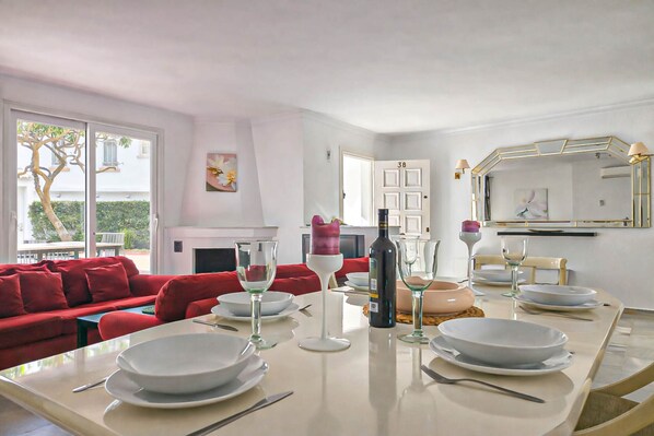 A dining area with a table set for four, a red sofa, and a fireplace in the background.