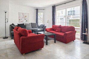 A modern living room with a grey sofa, a red sofa, and a coffee table. There is a painting on the wall and a floor lamp.