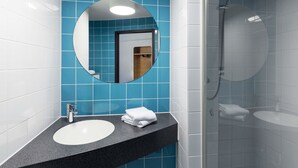 A bathroom with a round mirror, a sink, and a shower.