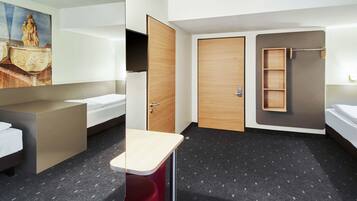 A modern hotel room with a bed, a desk, a wardrobe, and a shower area.
