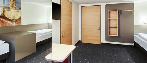 Una habitación de hotel moderna con cama, escritorio, armario y zona de ducha.