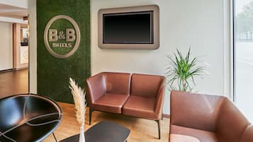 En hotellobby med en skylt som visar att det även finns bed and breakfast-rum, lädersoffor, en svart stol, ett litet bord och en krukväxt.