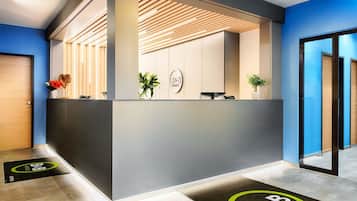 Een receptiegedeelte met een modern design, met een receptiebalie, een plant en een logo aan de muur.